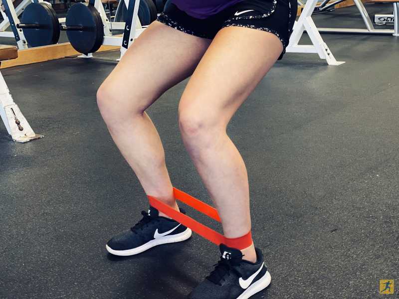 Close up of woman's knees and legs with resistance band on